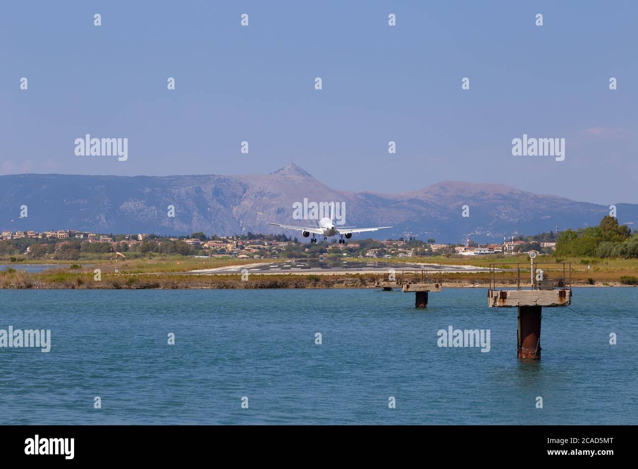 Passagierflugzeug landet am Flughafen Kerkyra. Griechenland, Insel Korfu. Verringern der Höhe. Start- und Landebahn im Hintergrund von Bergen und Meer. Stockfoto