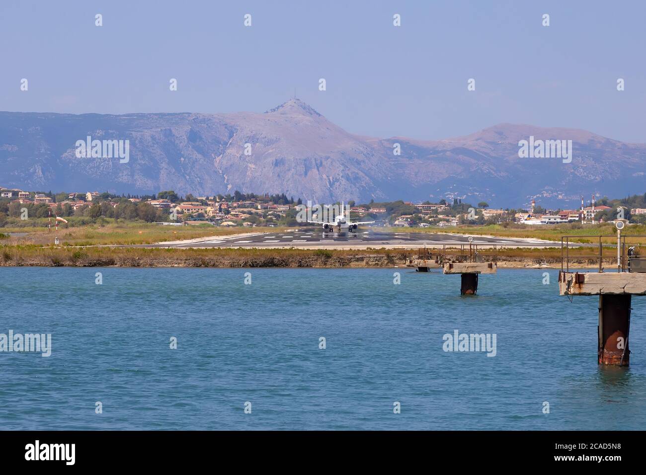 Passagierflugzeug landet am Flughafen Kerkyra. Griechenland, Insel Korfu. Verringern der Höhe. Start- und Landebahn im Hintergrund von Bergen und Meer. Stockfoto