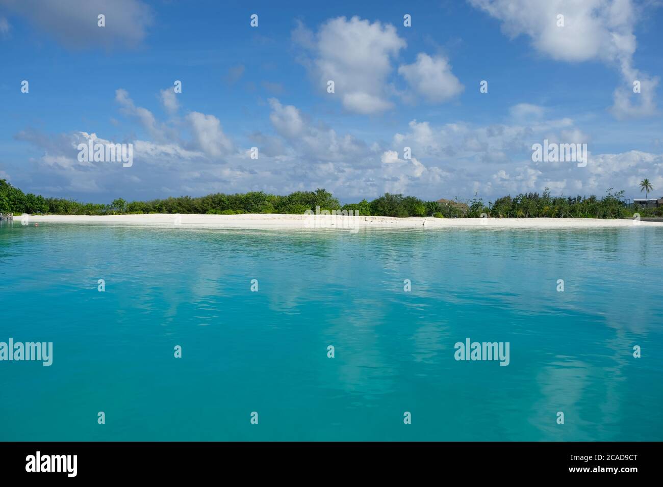 Weiße Wolke sonniger Himmel, schönes blaues Meerwasser, grüne Waldinsel am Horizont. Horizontales Maldive Island Resort. Stockfoto