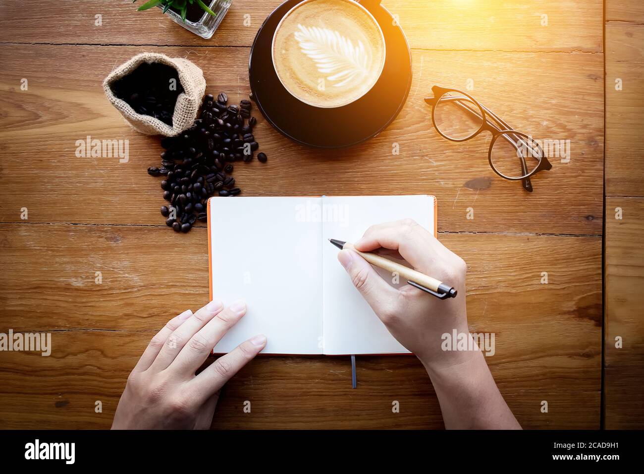 Barista Café Zubereitung von Kaffee Zubereitungsservice. Mann hält einen Stift Schreibnotiz auf leere weiße Seite mit Platz für Text auf vintage Schreibtisch Stockfoto