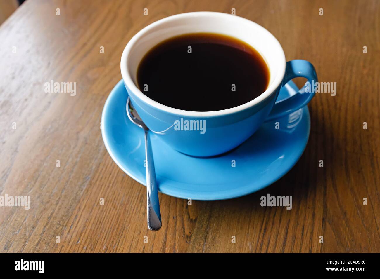 Blaue Tasse mit schwarzem Kaffee auf dem Holztisch Stockfoto