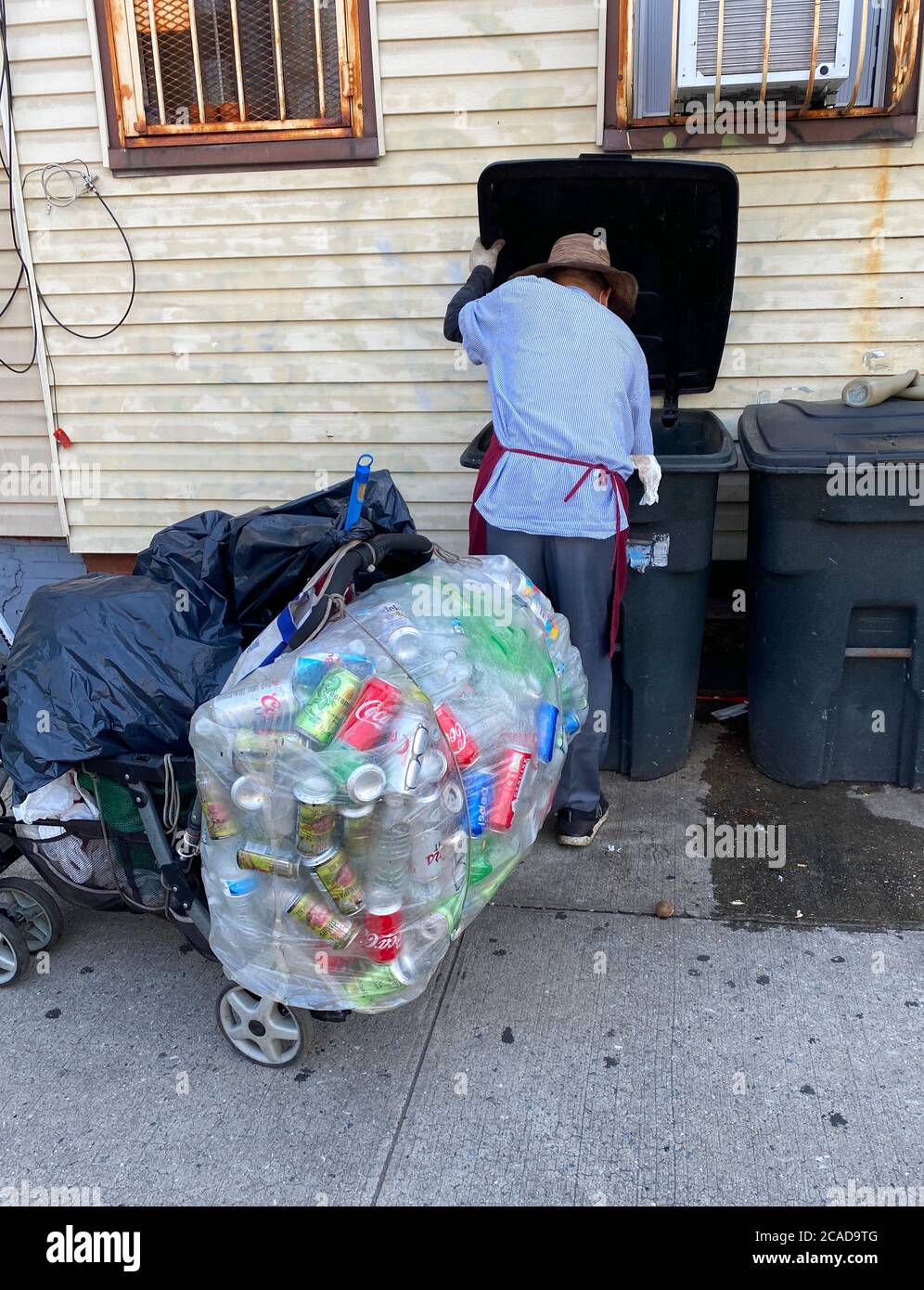 Der Mensch arbeitet hart daran, ausrangierte Aluminiumdosen zu sammeln, um ein Leben an einer Straße in Brooklyn, New York, zu kratzen. Stockfoto