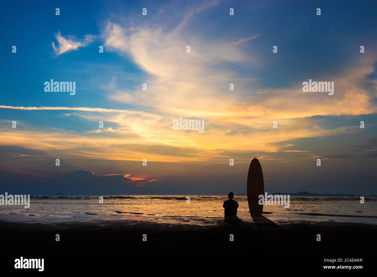 Silhouette des Surf-Mann sitzen mit einem Surfbrett am Strand. Surfszene am Strand bei Sonnenuntergang mit buntem Himmel. Outdoor Wassersport Abenteuer Lifestyle.sum Stockfoto