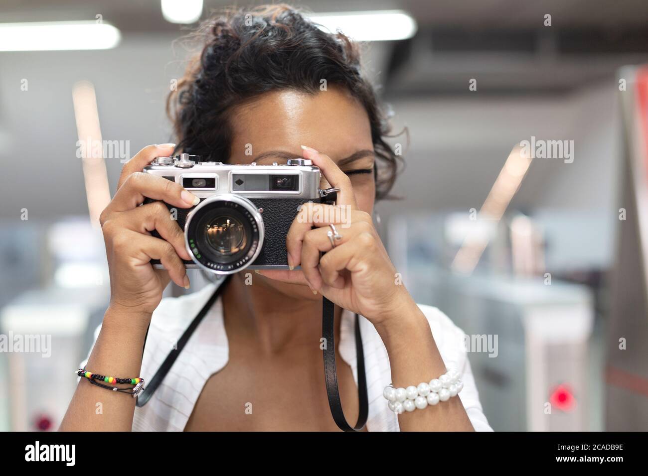 Nahaufnahme einer Frau mit exotischen Funktionen, die mit einer analogen Filmkamera fotografiert. Selektiver Fokus. Konzept von Reisen und Tourismus. Stockfoto