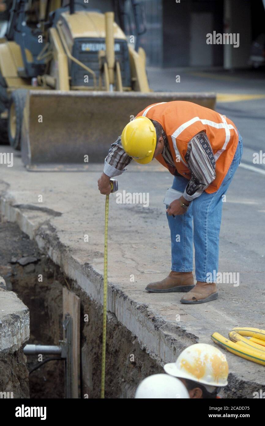 Austin Texas USA: Hispanische Bauarbeiter messen die Tiefe des Grabens unterhalb der Colorado Street, während die Besatzungen Glasfaserkabel durch die Innenstadt verlegen. ©Bob Daemmrich Stockfoto