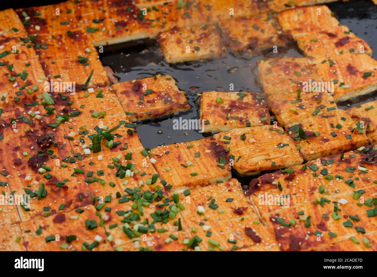 Nahaufnahme Stinky Tofu auf Bratpfanne mit grüner Zwiebel und Chili. Ein traditioneller chinesischer fermentierter Snack. Stockfoto