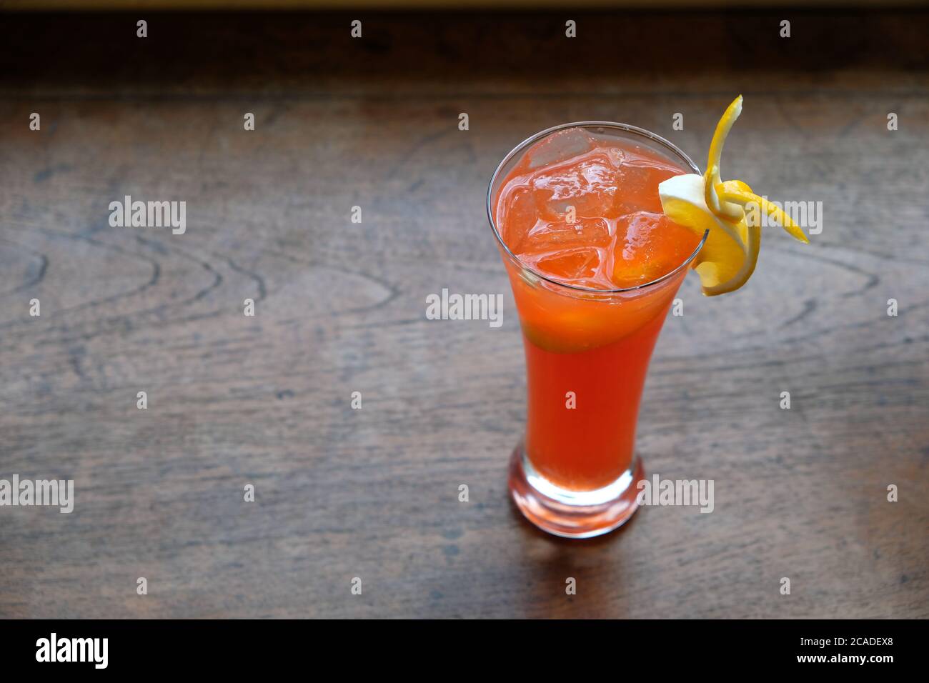Nahaufnahme ein Glas Orangencocktail mit Obstscheibe auf gemustertem Holztisch. Hintergrund verwischen Stockfoto