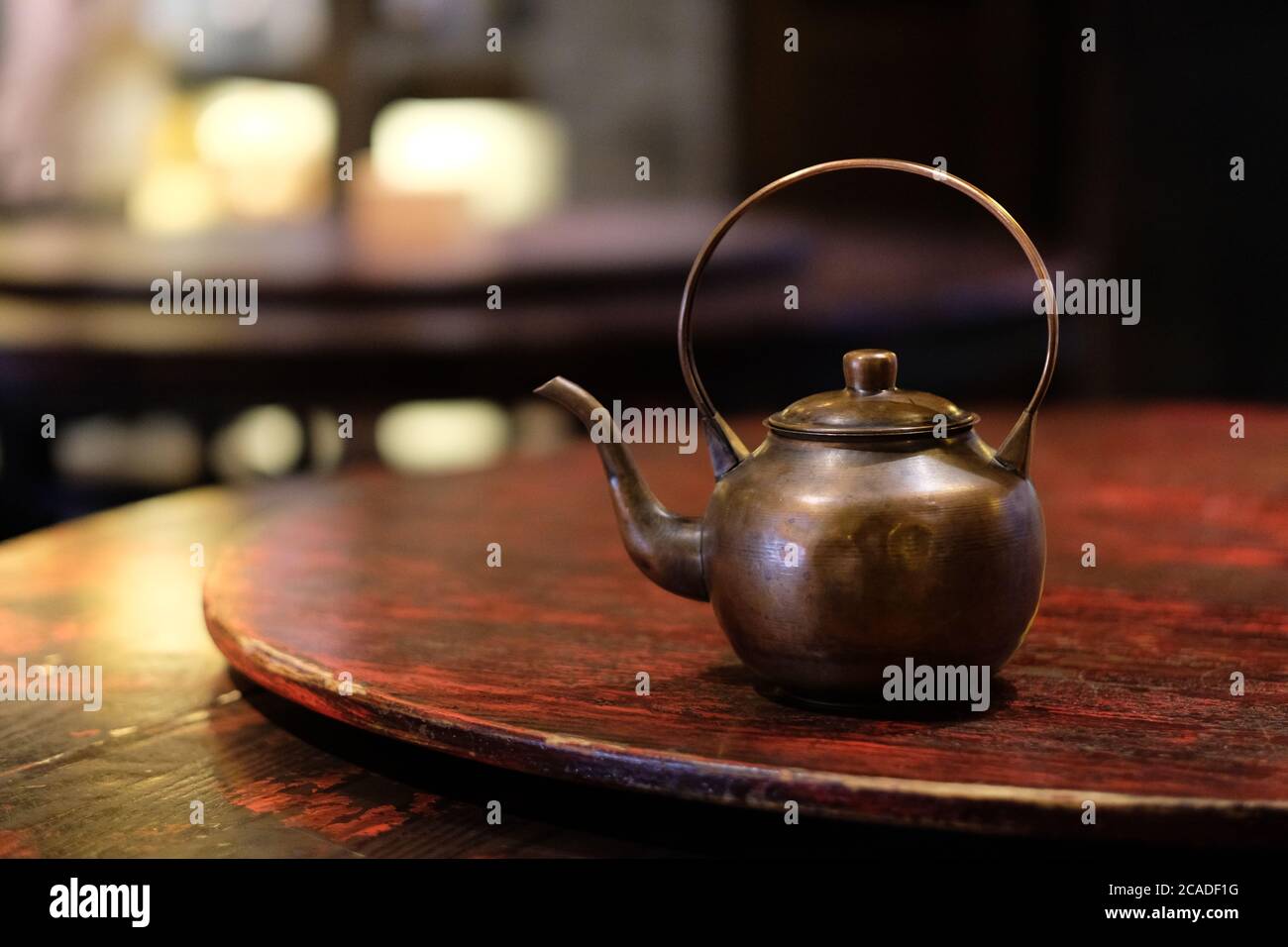 Schließen Sie eine alte Kupfer Teekanne auf Holztisch. Traditioneller chinesischer Teekocher. Bokeh-Hintergrund Stockfoto