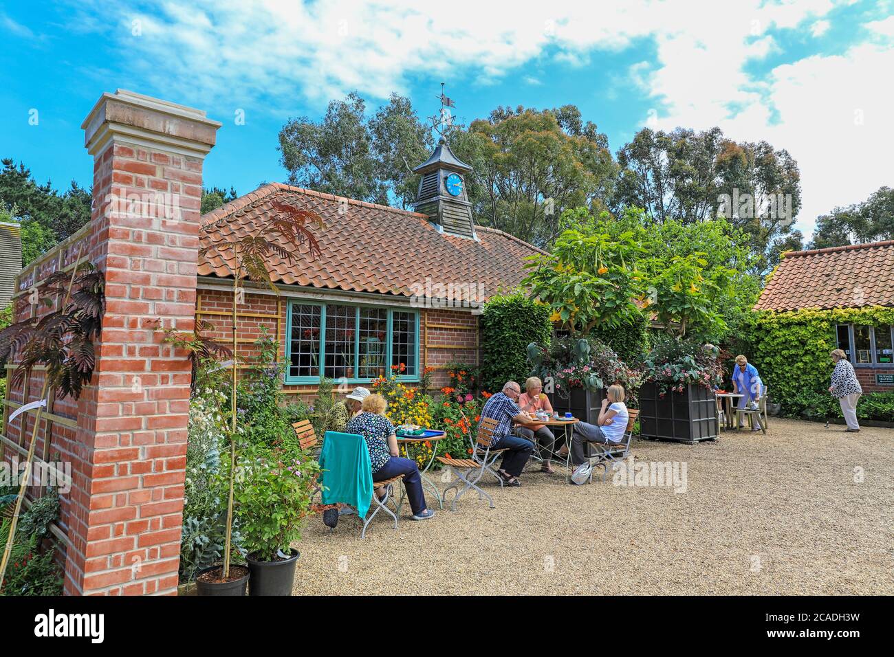 Leute, die draußen im Tea Garden im East Ruston Old Vicarage Garden, East Ruston, Norfolk, England, Großbritannien essen Stockfoto