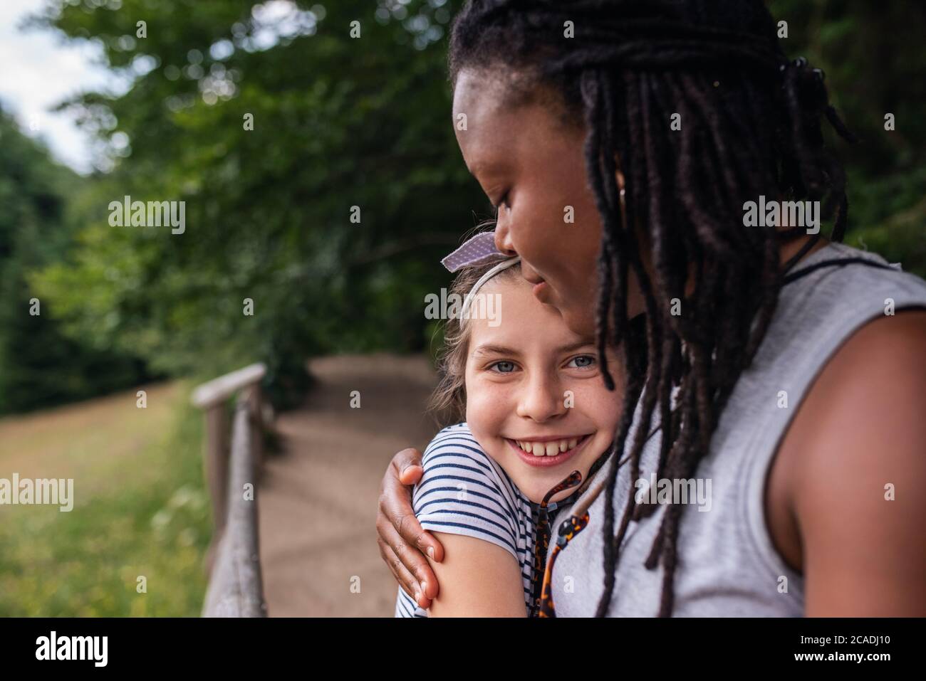 Portrait eines lächelnden kleinen Mädchens, das liebevoll ihren Freund umarmt, während er eine Pause von ihrer gemeinsamen Wanderung nimmt Stockfoto