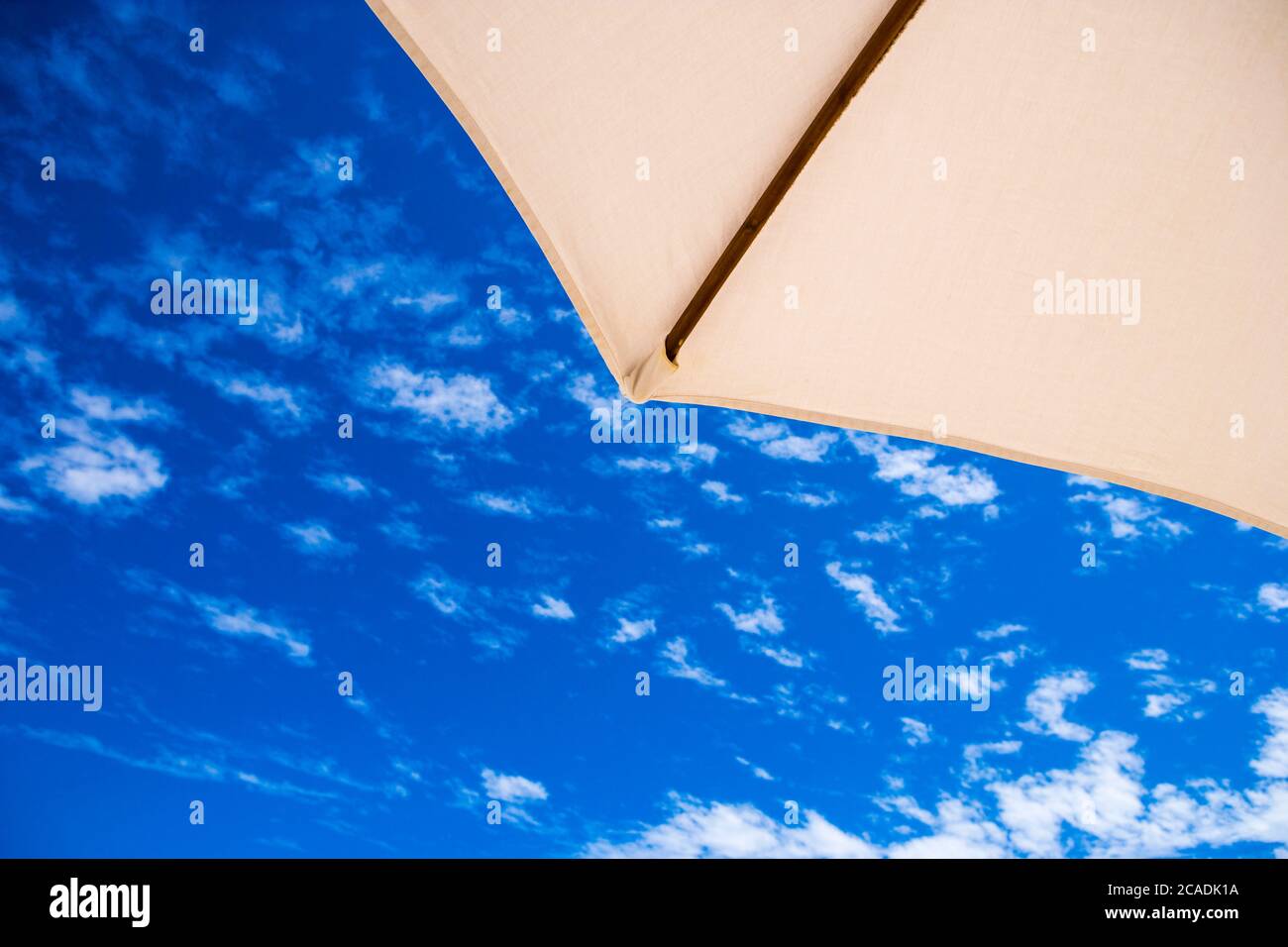 Ein Sonnenschirm Ecke gegen einen blauen Himmel mit Wölkchen Stockfoto