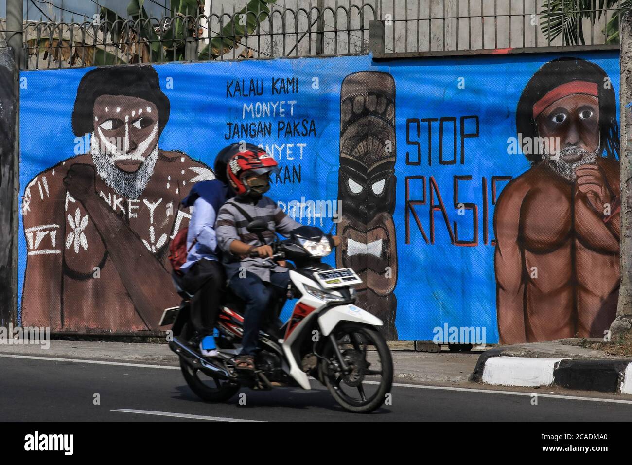 Depok, Indonesien. August 2020. Ein Motorradfahrer fährt an einem Wandbild vorbei, das eine dunkelhäutige Papua-Ureinwohner darstellt.das Wandbild setzt sich für die Öffentlichkeit gegen Rassismus ein.Indonesien hat 1,331 ethnische Gruppen mit unterschiedlichen Kulturen, Charakteren und Hautfarben. Mit dunkelfarbigen Menschen aus den Stämmen, die die Provinzen Papua und West Papua bewohnen. Gegenwärtig werden sie oft von Teilen der indonesischen Gesellschaft ungleich behandelt und Stigmatisierung erfahren. Kredit: SOPA Images Limited/Alamy Live Nachrichten Stockfoto