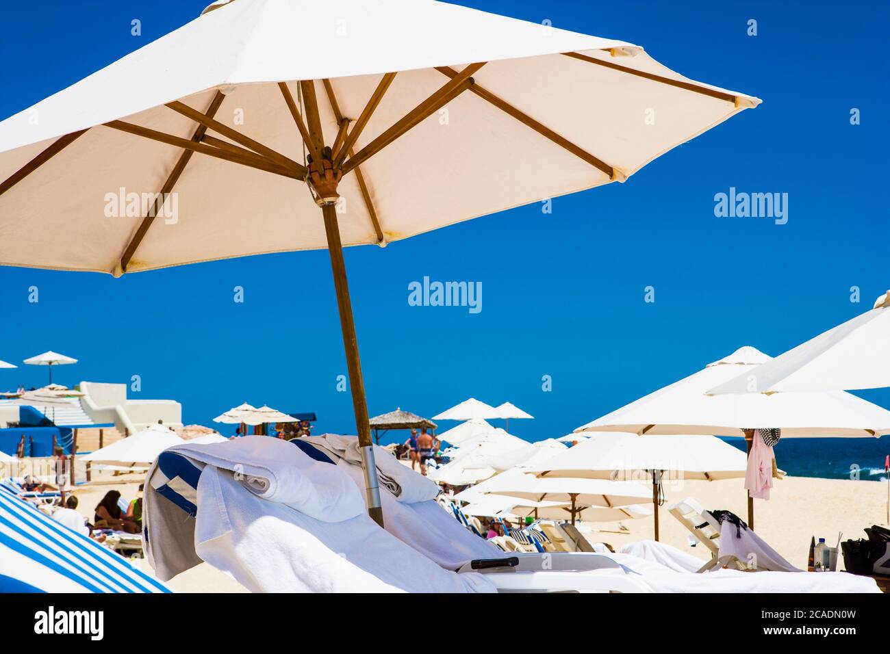 Low-Angle-Ansicht, Sonnenliegen und Sonnenschirme am Strand, blauer Himmel Hintergrund Stockfoto