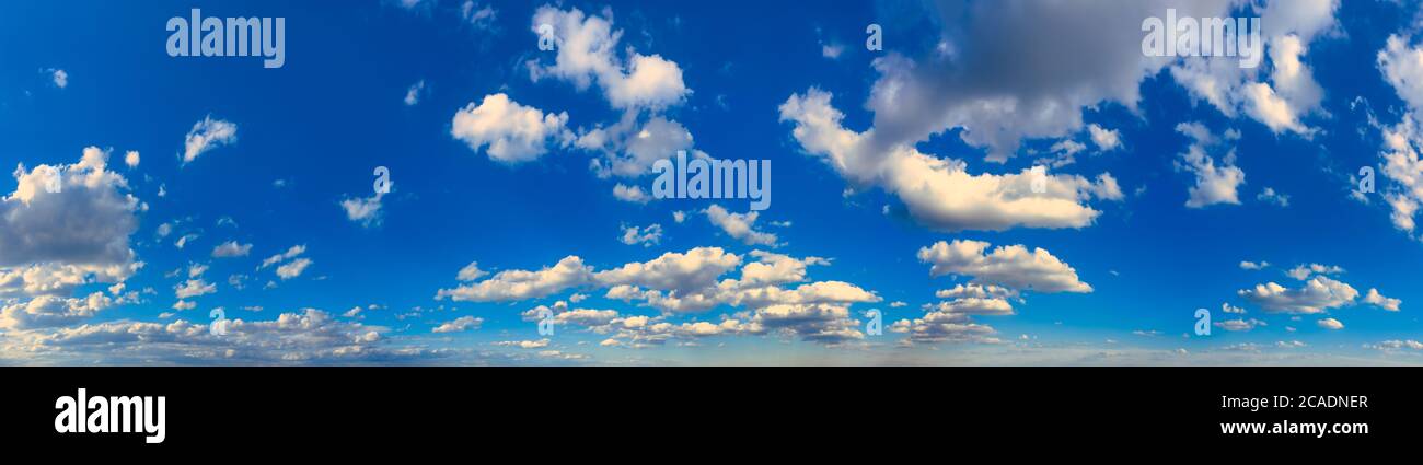 Weiße Cumulus Wolken in blauem Himmel in großer Höhe bei Tageslicht am Nachmittag. Ultrabreites Panorama. Stockfoto