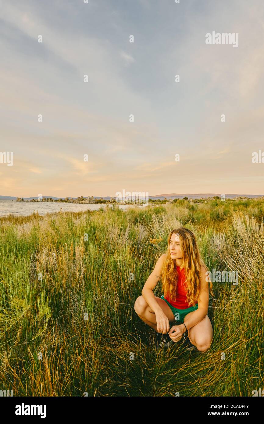 Junge Frau, die im hohen Gras am Mono Lake im Norden Kaliforniens sitzt. Stockfoto