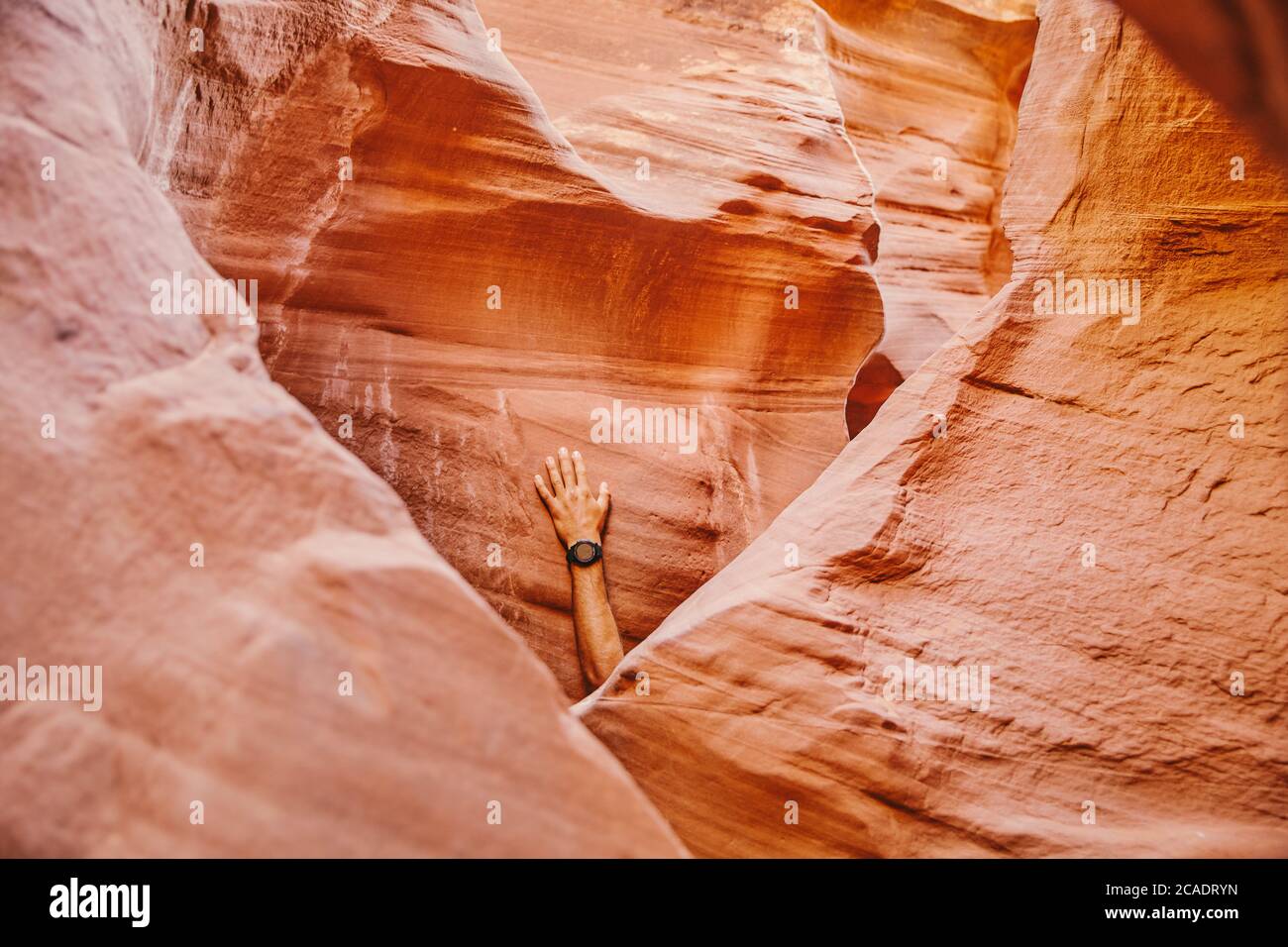 Hand mit Fitnessuhr gegen Slot Canyon Wand in Escalante, Utah. Stockfoto
