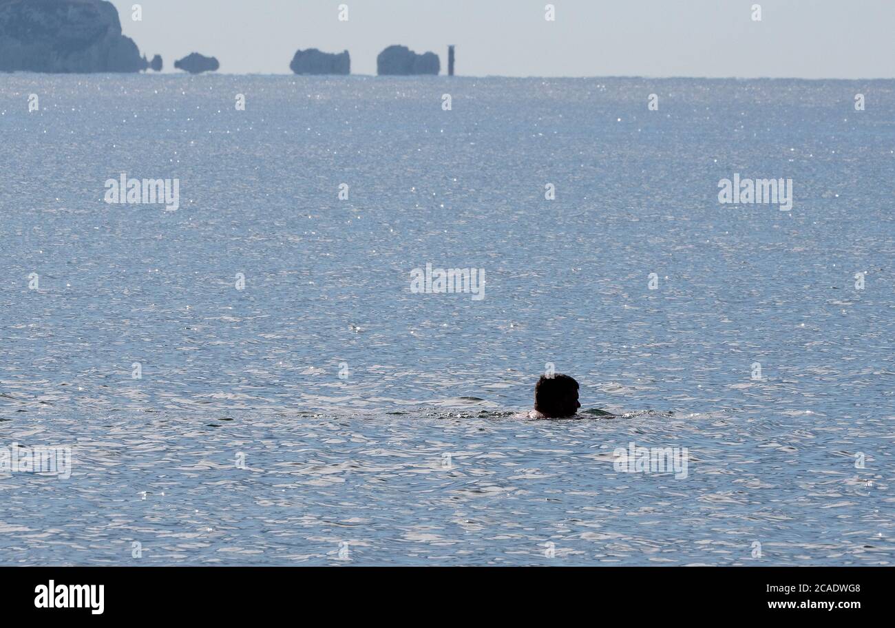 Schwimmer im Meer mit den Nadeln auf der Isle of Wight im Hintergrund. Stockfoto
