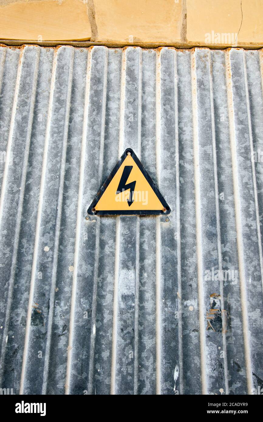 Warnschild für elektrischen Schlag am Eingang der Wellblechtür Stockfoto