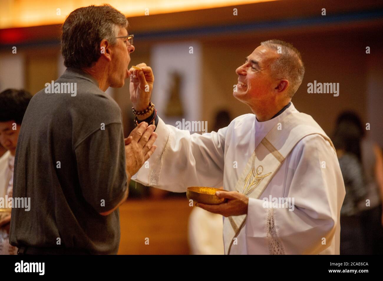 Ein Robed Diakon bietet eine Kommunion Wafer zu einem Anbeter während der Messe in einer Tustin, CA, katholische Kirche. Stockfoto
