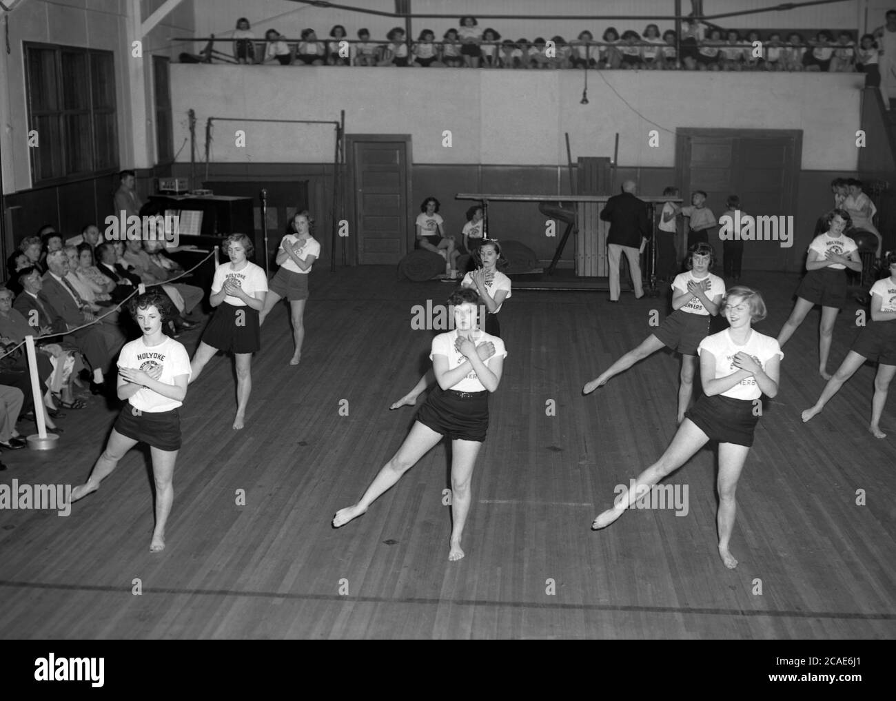 Um 1940er Jahre, historische, weibliche Gymnasiasten in einem Fitnessstudio, die eine künstlerische oder bodengymnastische Ausstellung vor Eltern und Gästen machen, MA, USA. Stockfoto