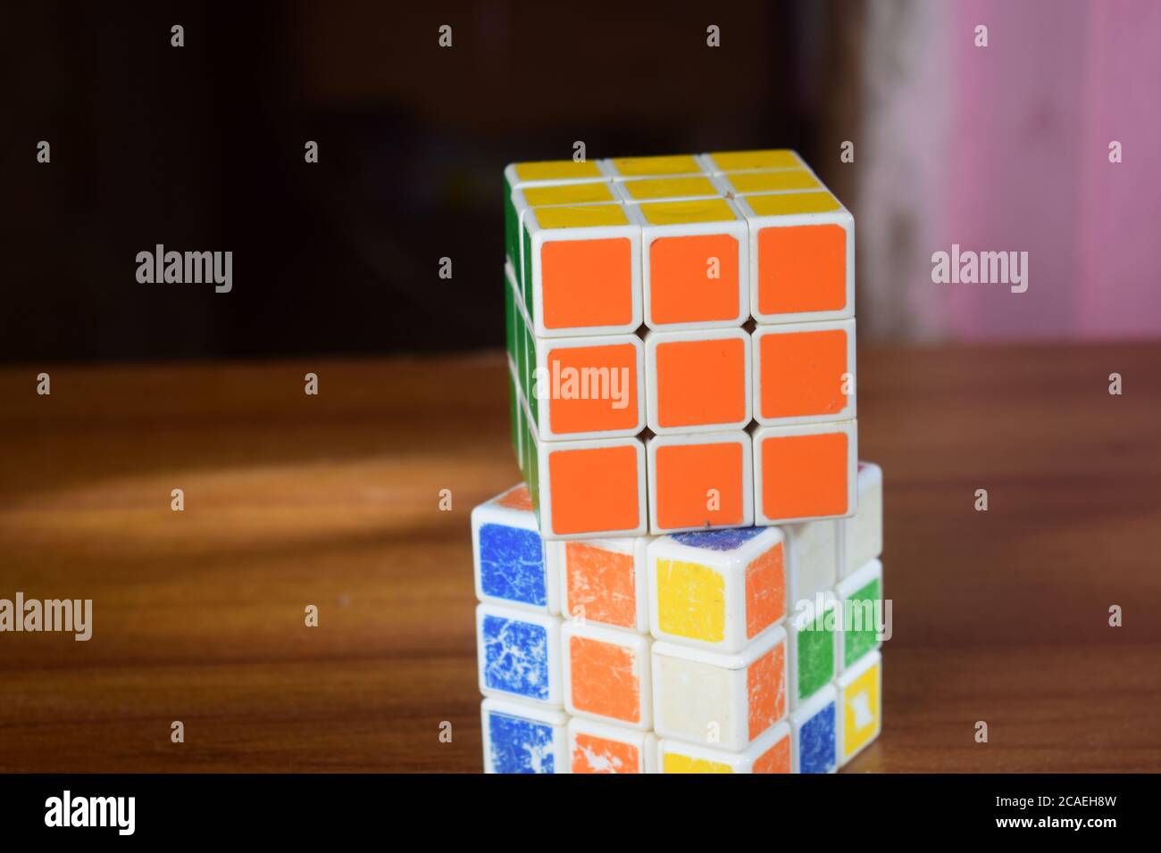 Nahaufnahme eines gelösten Rubik-Würfels auf einem ungelösten Würfel Auf dem Tisch mit verschwommenem Hintergrund Stockfoto