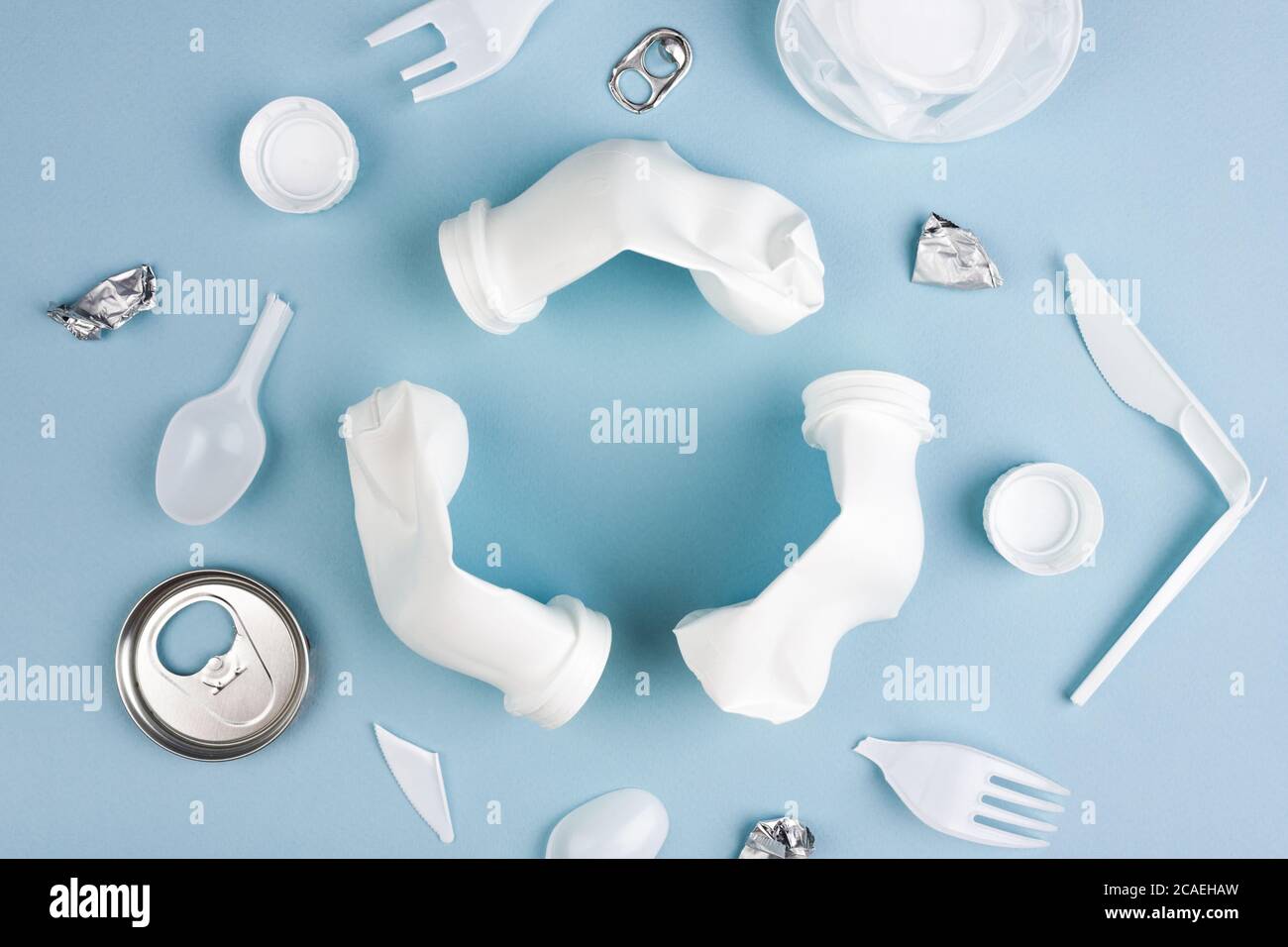 Weißes Recycling-Zeichen aus Kunststoff-Flaschen mit verschiedenen Plastikmüll auf blauem Hintergrund flach lag mit Kopierraum erstellt. Stockfoto