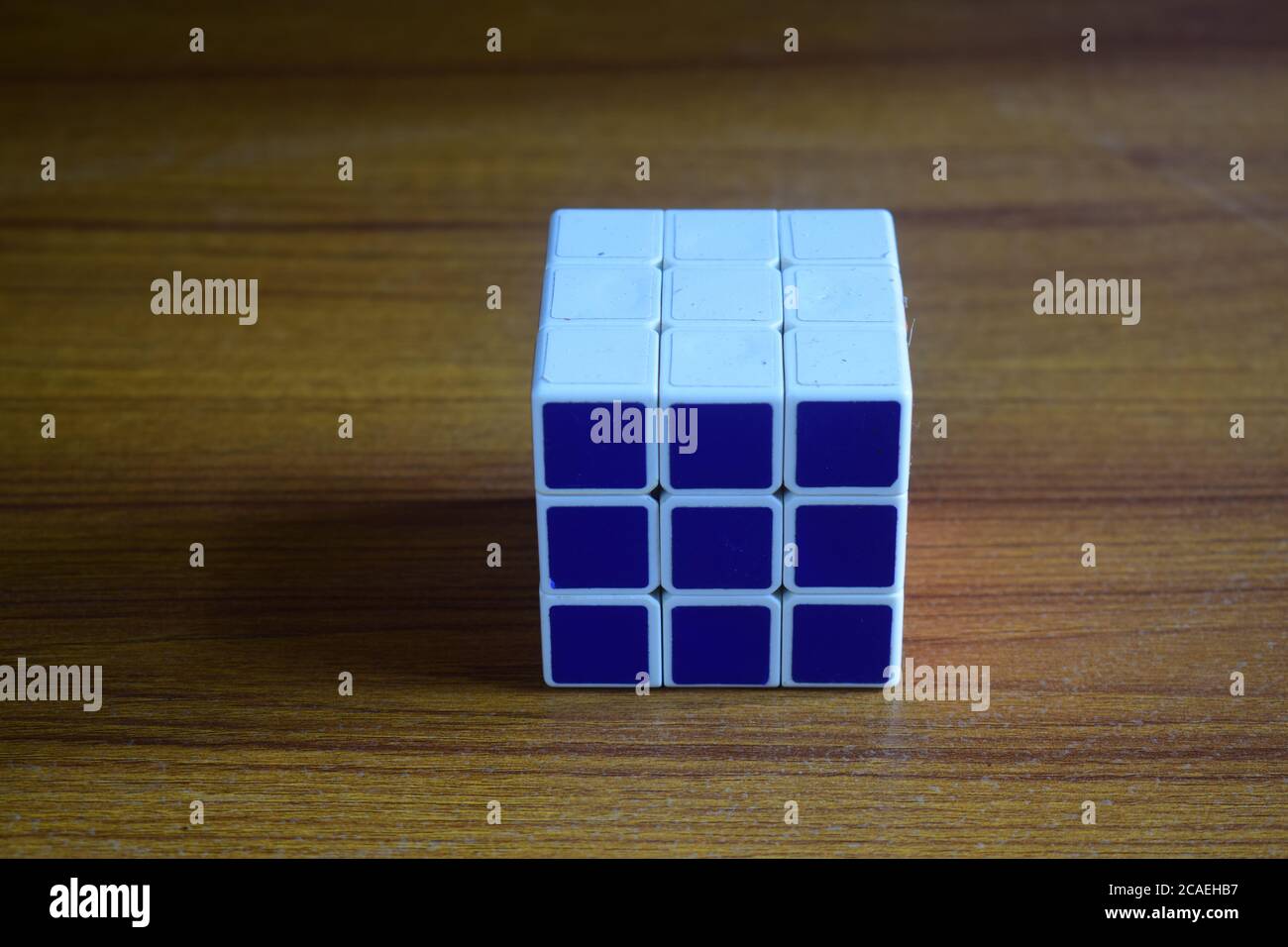 High-Angle-Ansicht eines gelösten Rubik-Würfels auf einem Holztisch unter den Lichtern Stockfoto