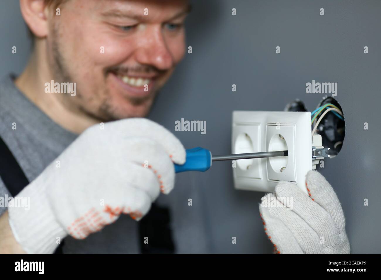 Handyman mit Schraubendreher, um Buchsen zu installieren Stockfoto