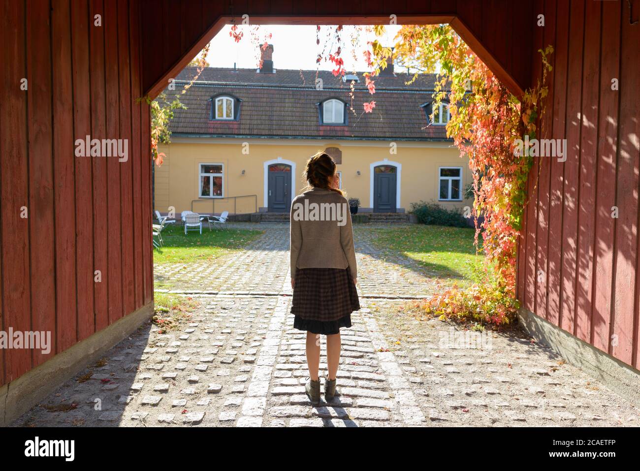 Rückansicht der jungen Frau, die im hölzernen Eingang des eleganten Vorstadthauses steht Stockfoto