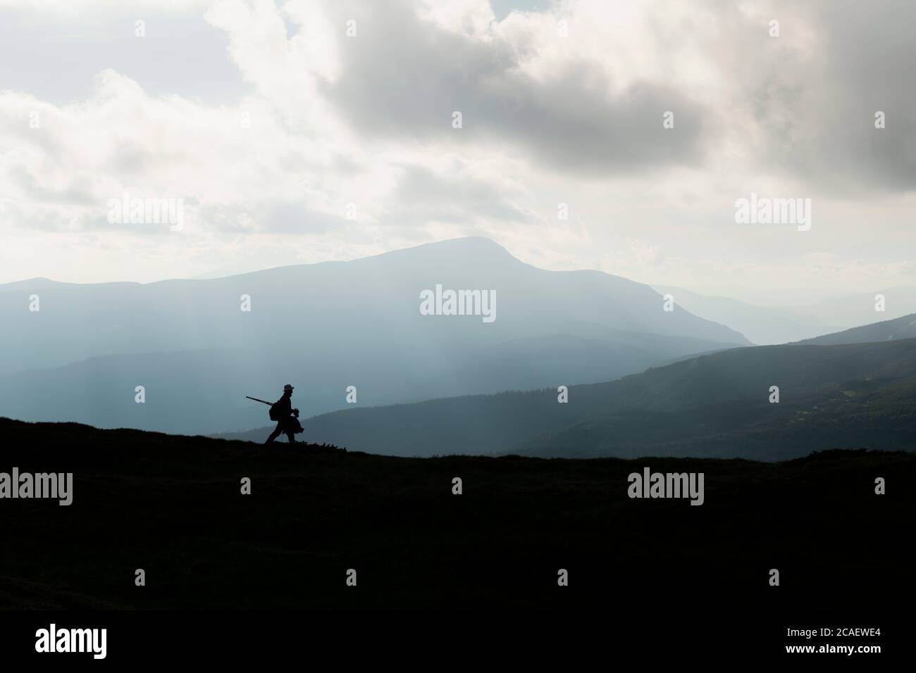Eine Silhouette eines Fotografen mit Stativ vor der Kulisse der majestätischen Berge. Landschaftsfotografie Stockfoto