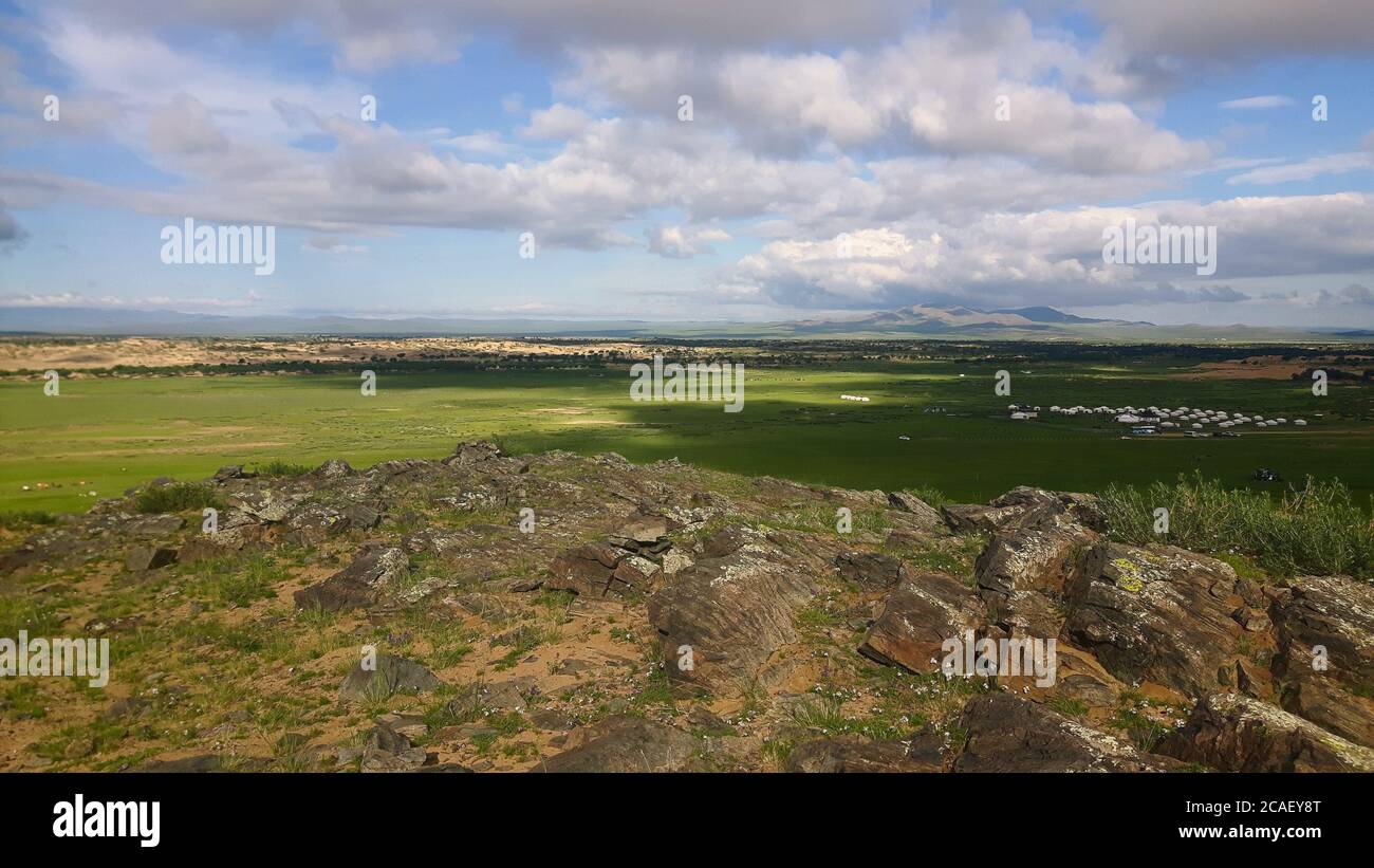 Ein atemberaubender Blick auf die abgelegene mongolische Landschaft, mit Gras- und Sandebenen und einer Sammlung von Jurten Stockfoto