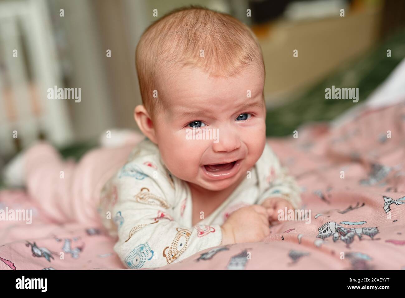 Neugeborenes Weinen, traurige Emotionen, Kind liegt auf dem Bauch kann nicht kriechen, traurig und traurig aussehen Stockfoto
