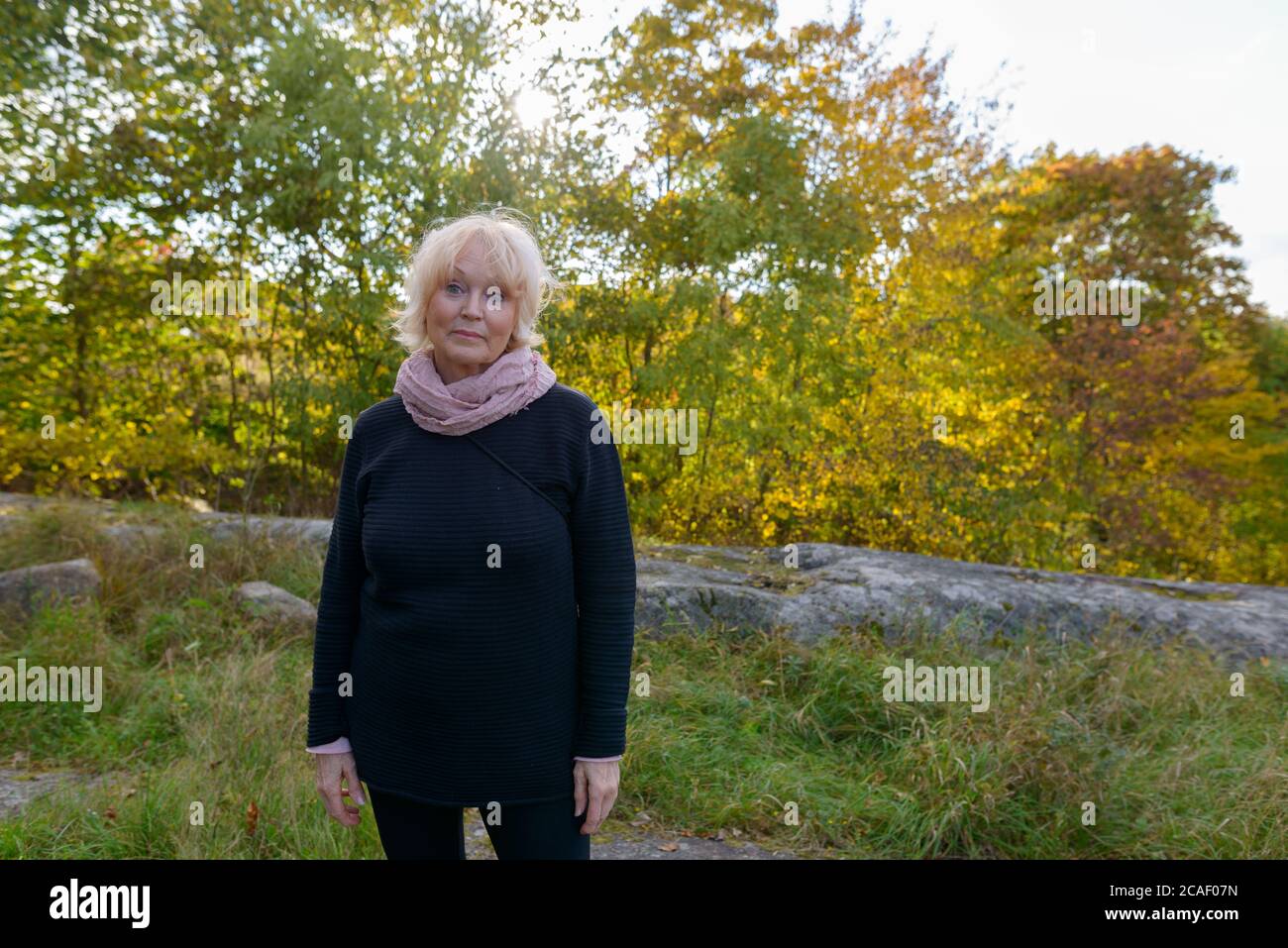 Ältere Frau, die vor einer wunderschönen Landschaft in den Bergen steht Stockfoto