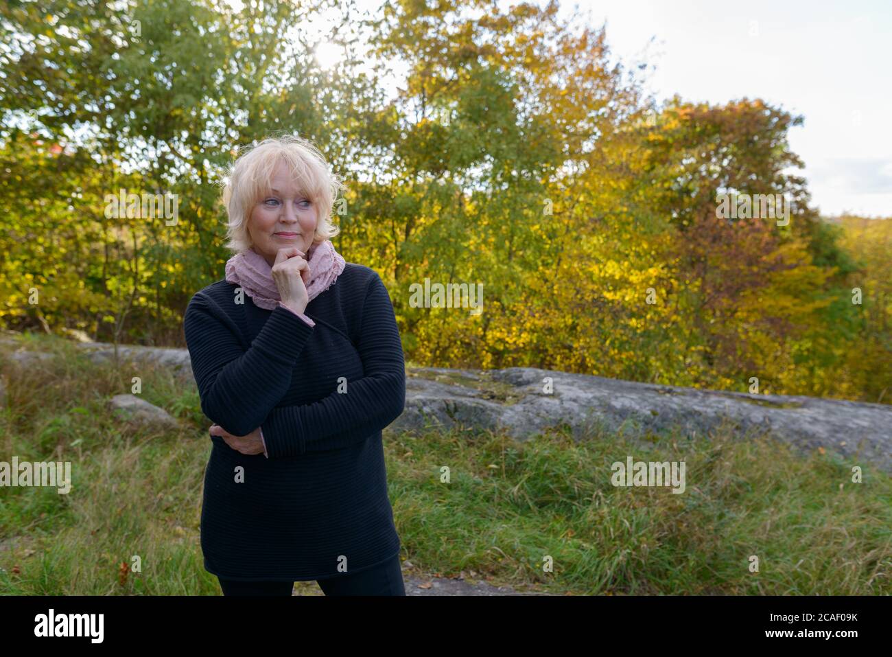 Ältere Frau, die vor einer wunderschönen Landschaft in den Bergen denkt Stockfoto