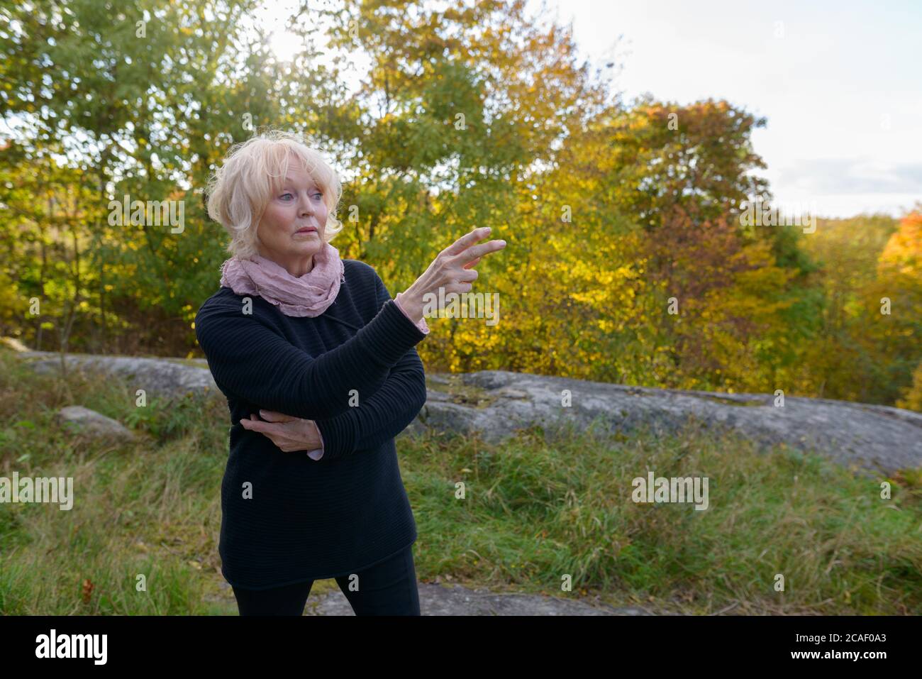 Ältere Frau zeigt mit dem Finger vor die wunderschöne Landschaft in den Bergen Stockfoto