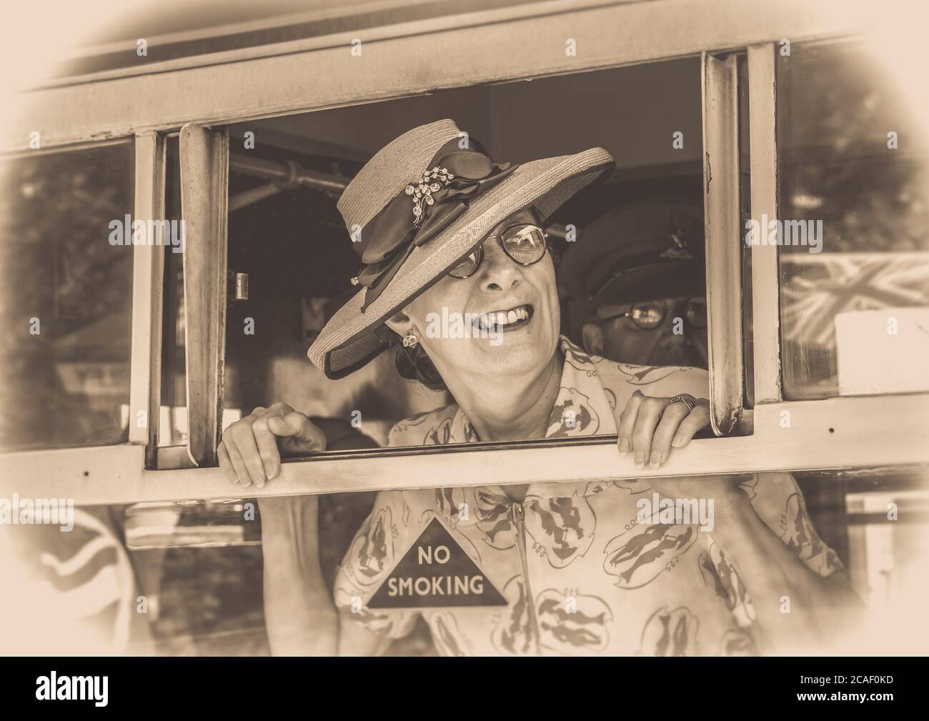 Sepia Nahaufnahme einer Frau aus den 1940er Jahren im Hut an Bord eines alten Eisenbahnwagens, mit Blick auf das Dampfzugfenster, die Freunden auf der Arley-Plattform Auf Wiedersehen sagte. Stockfoto