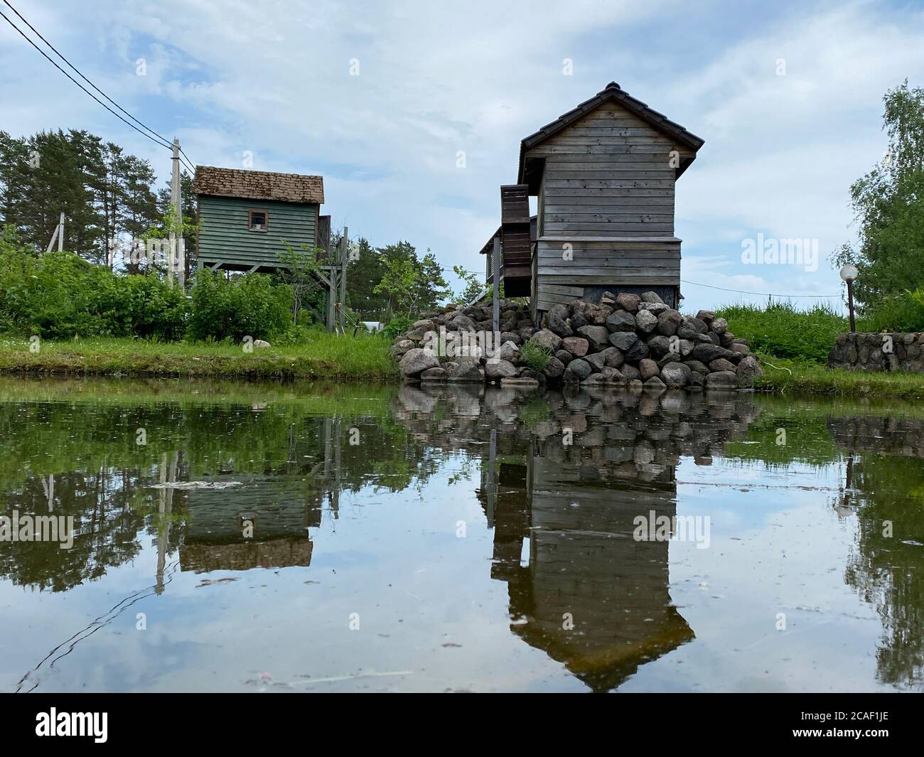 Altes Holzhaus, eine Hütte in einem Dorf mit einem kleinen Fenster befindet sich in der Nähe eines Teiches Stockfoto