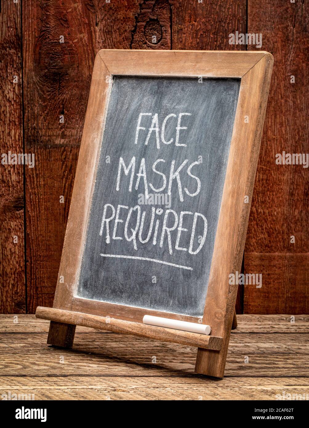 Gesichtsmasken erforderlich - weiße Kreide Handschrift auf einer Tafel, Coronavirus covid-19 Pandemiekonzept Stockfoto