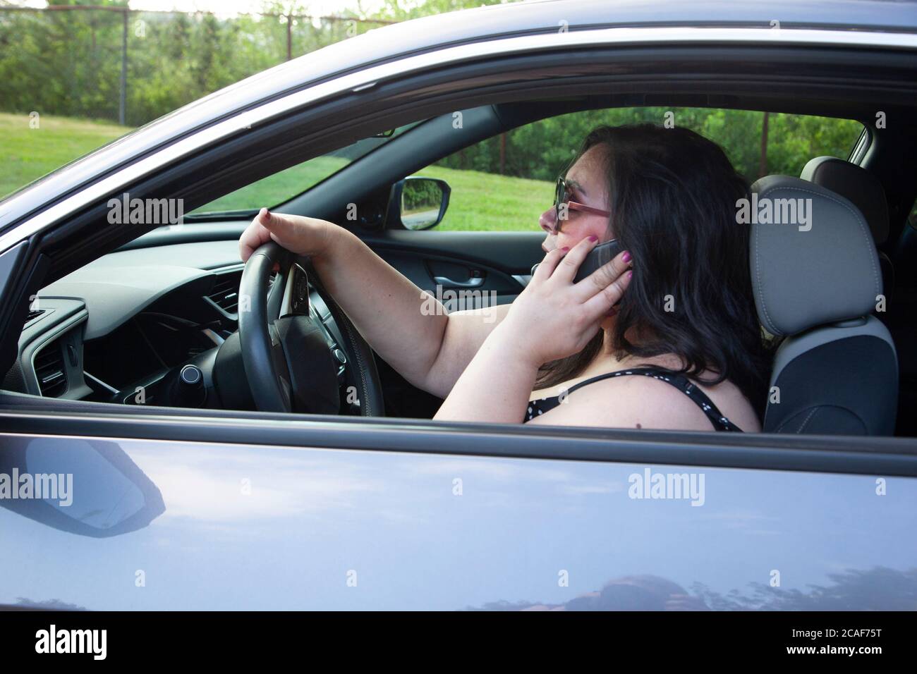 Frau, die mit dem Auto unterwegs war, auf ihrem Handy Stockfoto