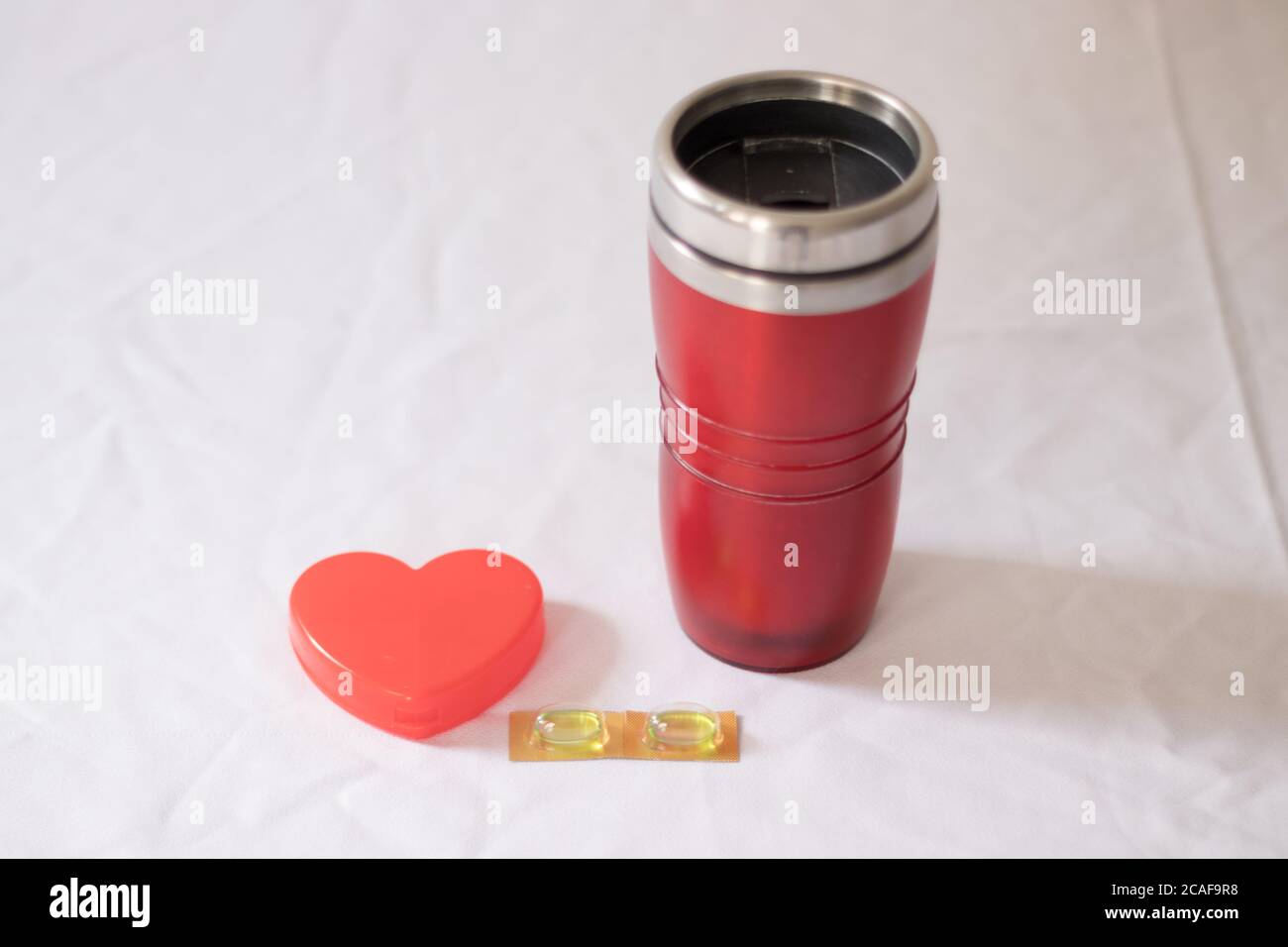 Pillen und Thermoskanne Tasse mit Herz Stockfoto