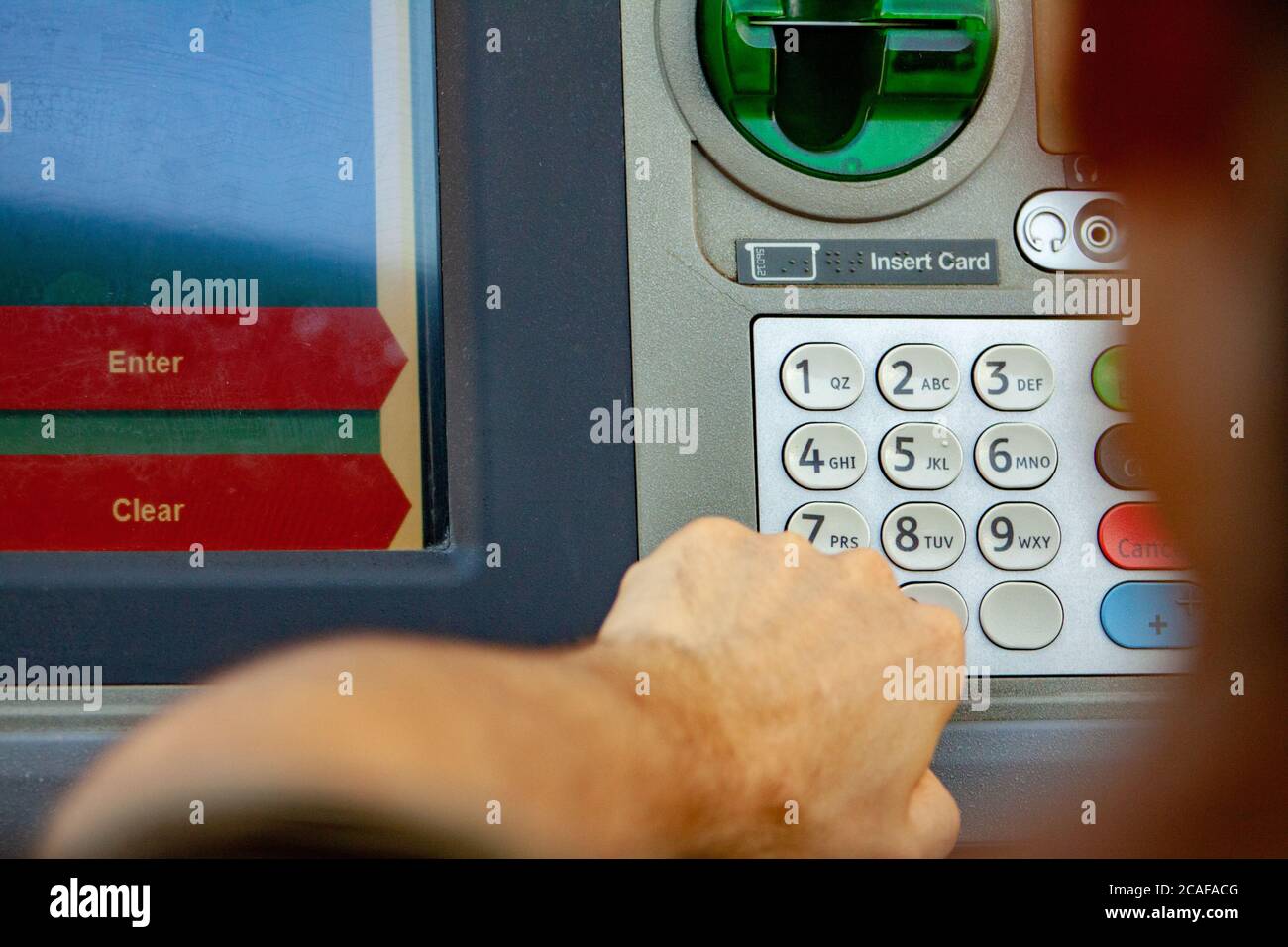 Mann an einer Bank Drive-Thru Geldautomat drückt auf Tastatur Neben dem Bildschirm, um Bargeld abzuheben Stockfoto