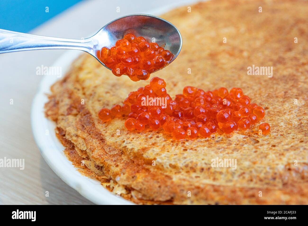 Pfannkuchen auf einem Teller mit rotem Kaviar und Löffel. Stockfoto