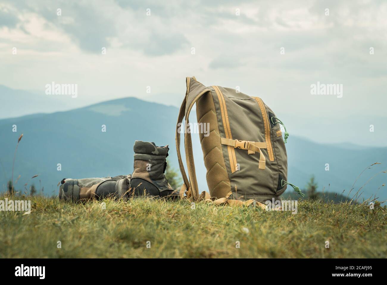 Khaki Farbe Stiefel und Rucksack auf einem Gras auf einem Berg Hügel stehen. Wandertourismus Konzept Stockfoto
