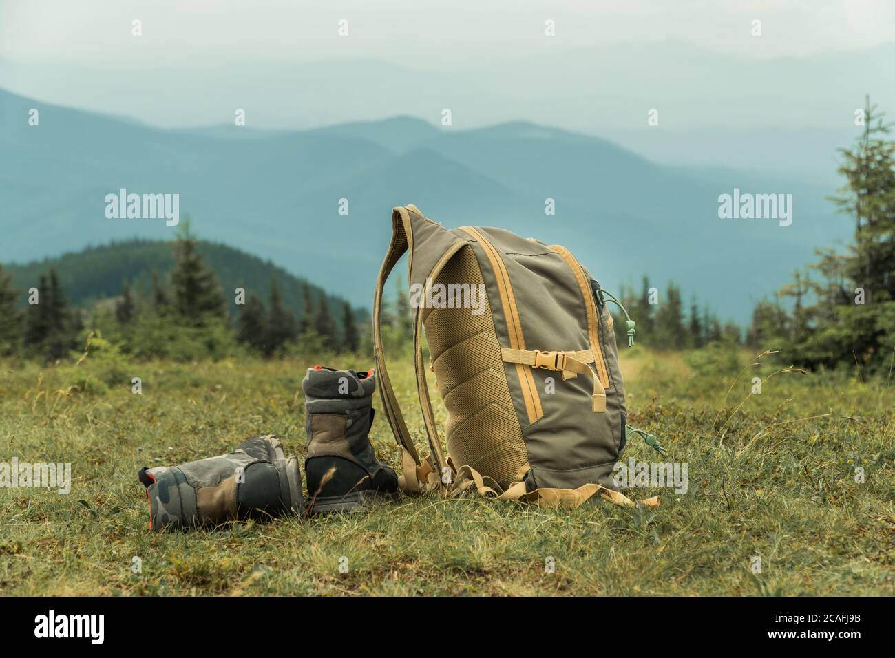 Khaki Farbe Stiefel und Rucksack auf einem Gras auf einem Berg Hügel stehen. Wandertourismus Konzept Stockfoto