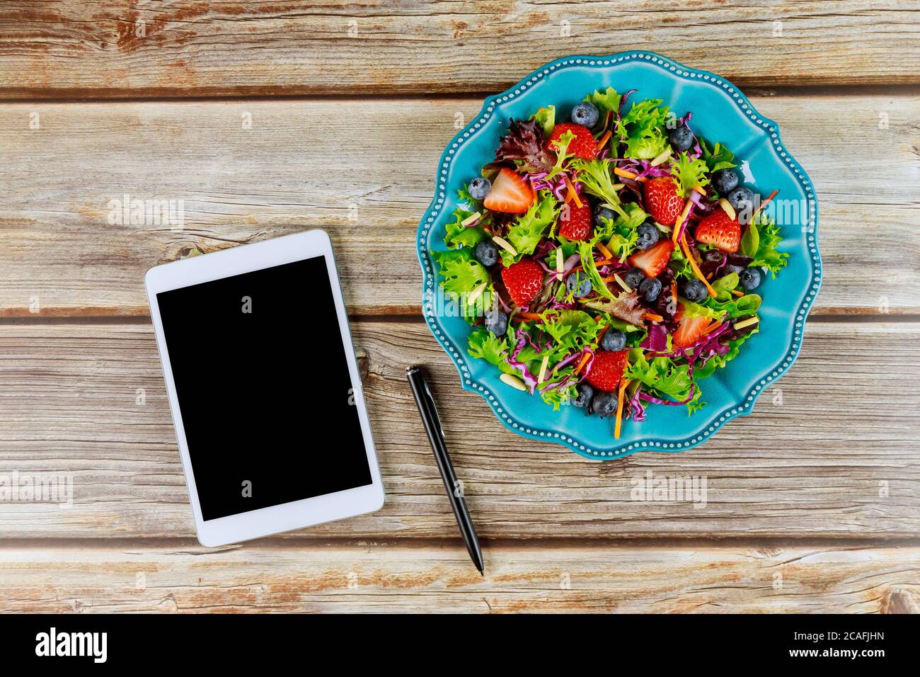 Farbenfroher Obst- und Gemüsesalat mit Tablett auf Holzhintergrund. Stockfoto