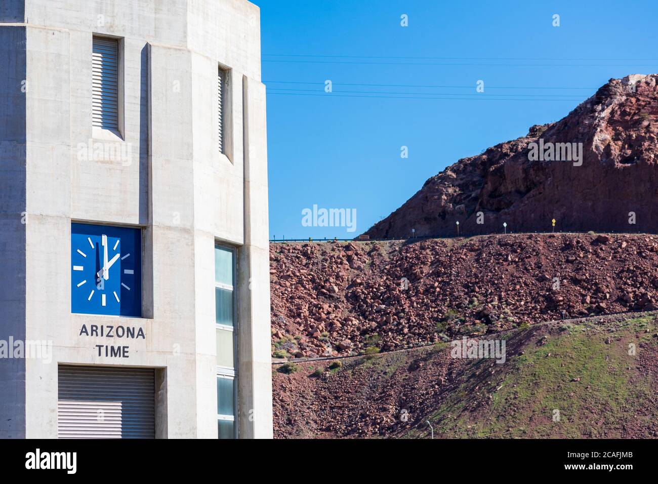 Wassereinlaufturm mit einer Uhr, die die Arizona-Zeit auf der Arizona-Seite des historischen Hoover Dam anzeigt. Felsige Wüstenlandschaft Hintergrund - Las Vegas, Ne Stockfoto