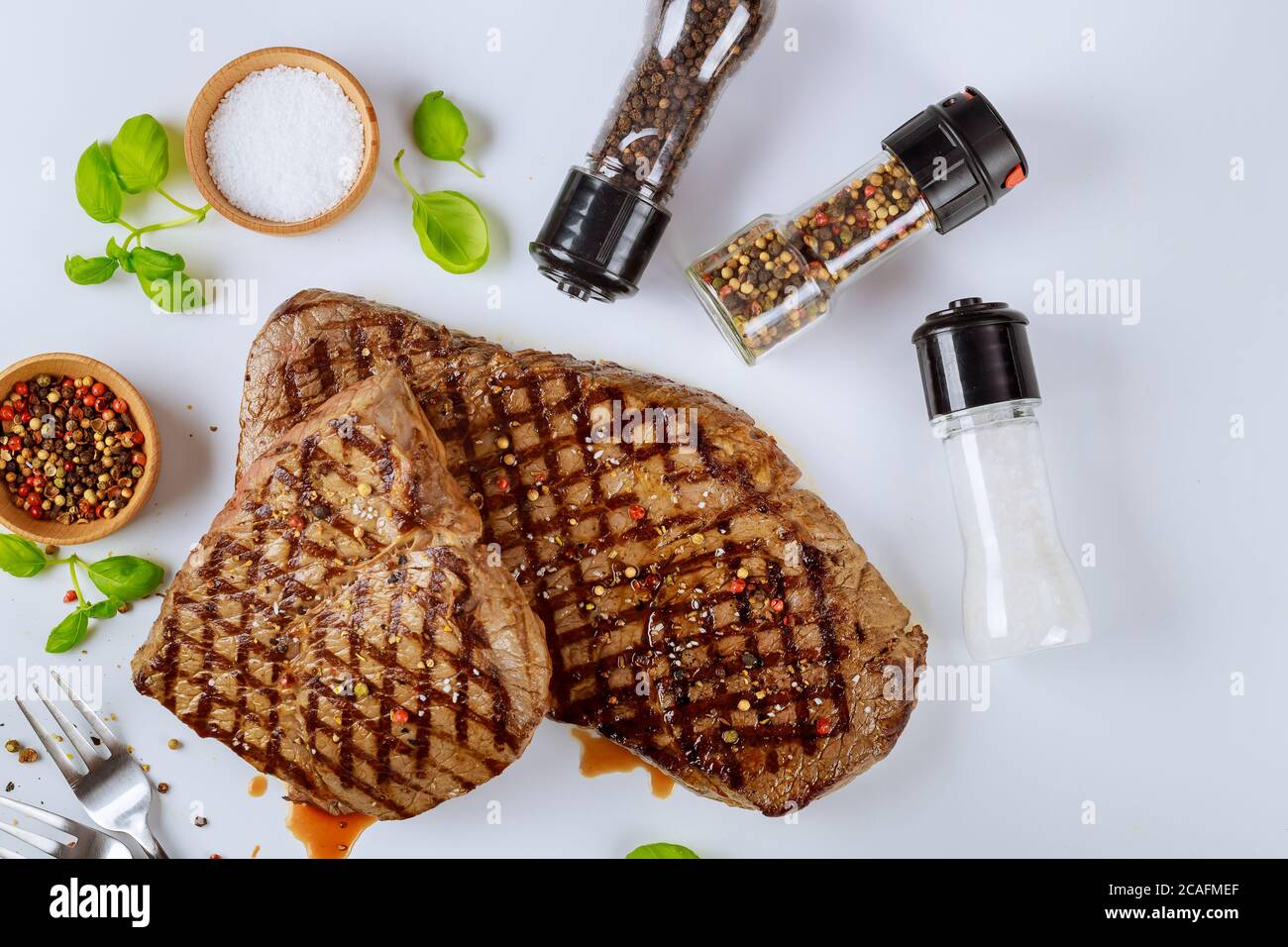 Zwei gegrillte Rindersteaks mit Würze isoliert auf weißem Hintergrund. Stockfoto