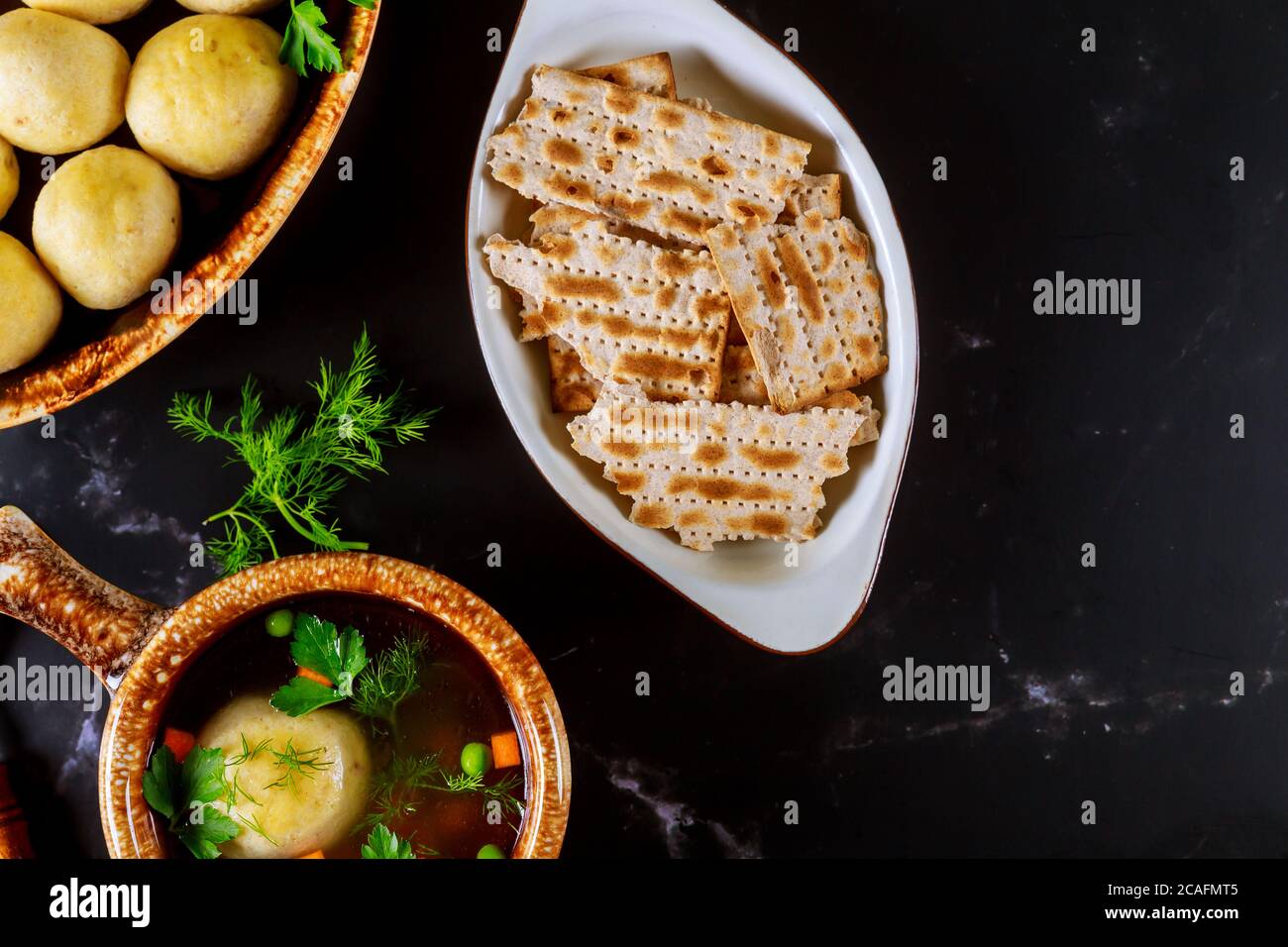Schüssel mit jüdischen Matzohkugeln Suppe mit Matzos auf schwarzem Hintergrund. Stockfoto