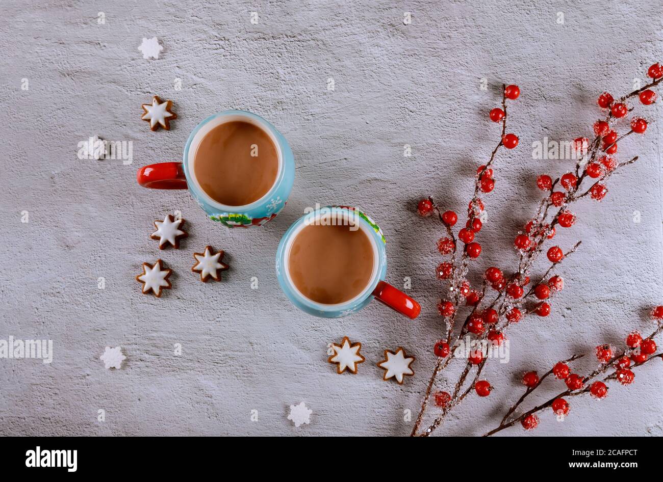 Zwei Tassen Kaffee auf weißem Tisch mit rotem Beerenzweig und Ingwerkeks. Stockfoto