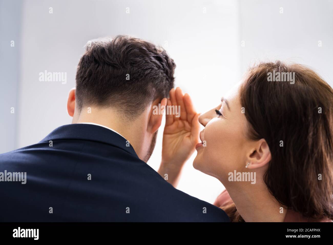 Frau flüstert Klatsch in Friends Ohr am Arbeitsplatz im Büro Stockfoto